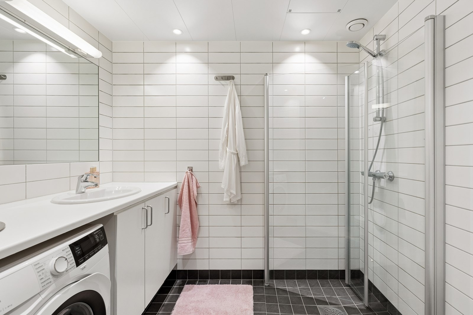 Badet er utstyrt med servant med underskap, vegghengt toalett, dusjløsning og opplegg for vaskemaskin Galleribilde