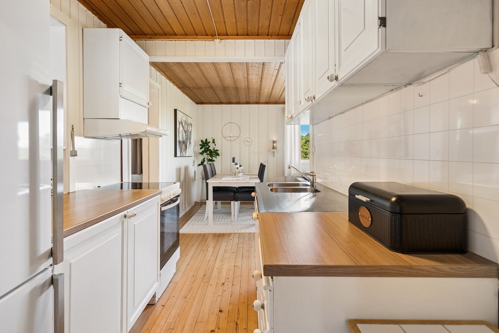Kjøkkenet har hvite over- og underskap med benkeplate av laminat og backsplash over benk. Vegger er kledd med malt trepanel, himlingen er ubehandlet paneltak og gulvet er tregulv. Galleribilde