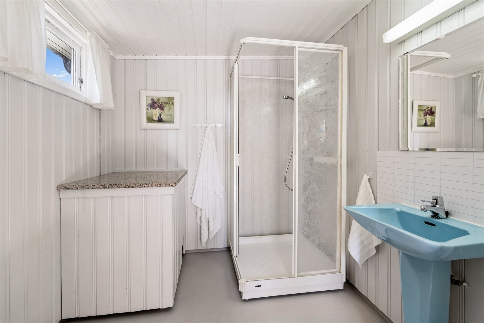 Gulv er belagt med belegg, vegger er kledd med trepanel og himling er malt trepanel. Varmtvannsbereder av merket Høiax og hovedstoppekran er plassert på badet. Vann- og avløpsrør er i plast, og det er sluk under dusjkabinett. Galleribilde