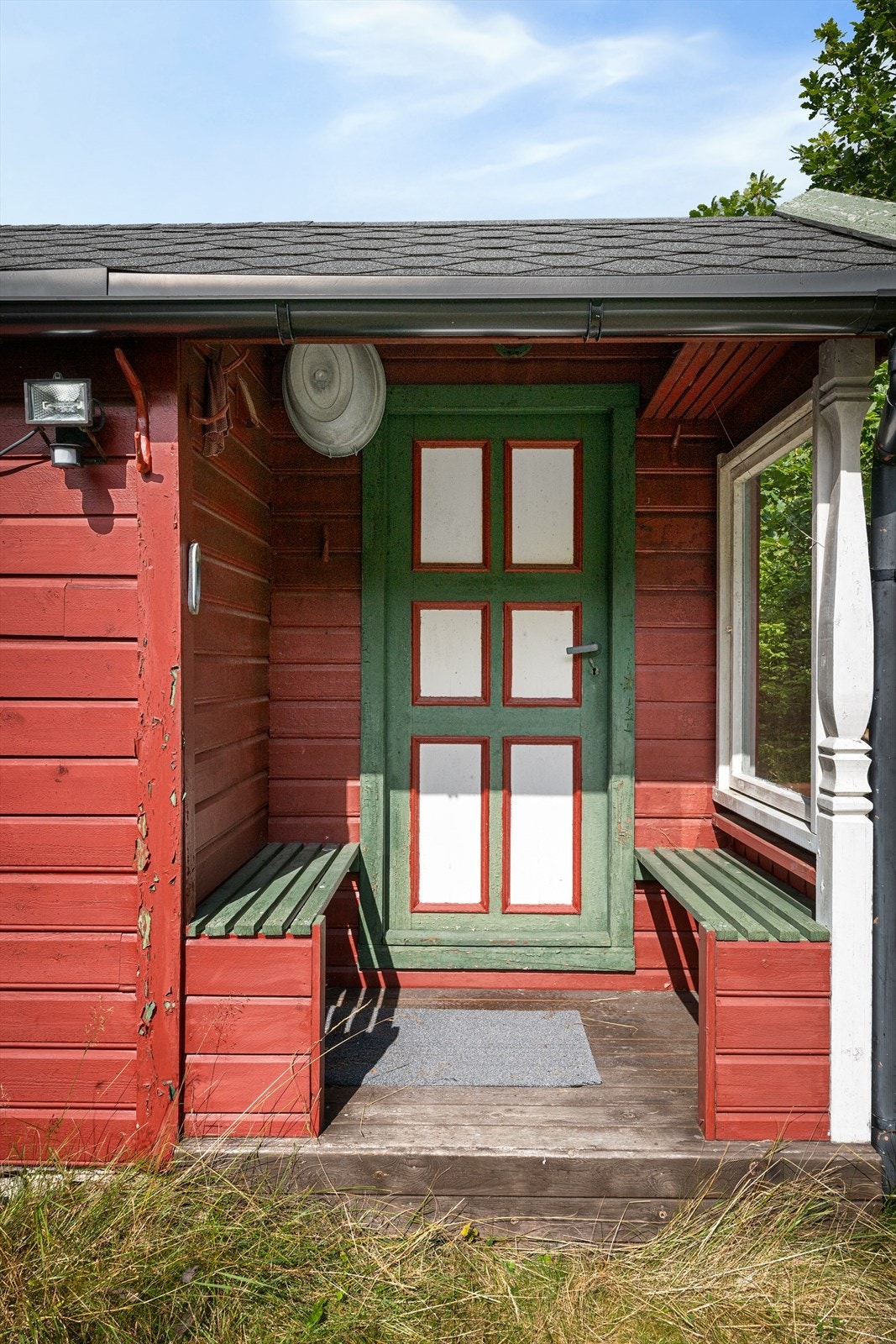 Et sjarmerende, overbygget inngangsparti med sittebenker ønsker deg velkommen til hytten. Galleribilde