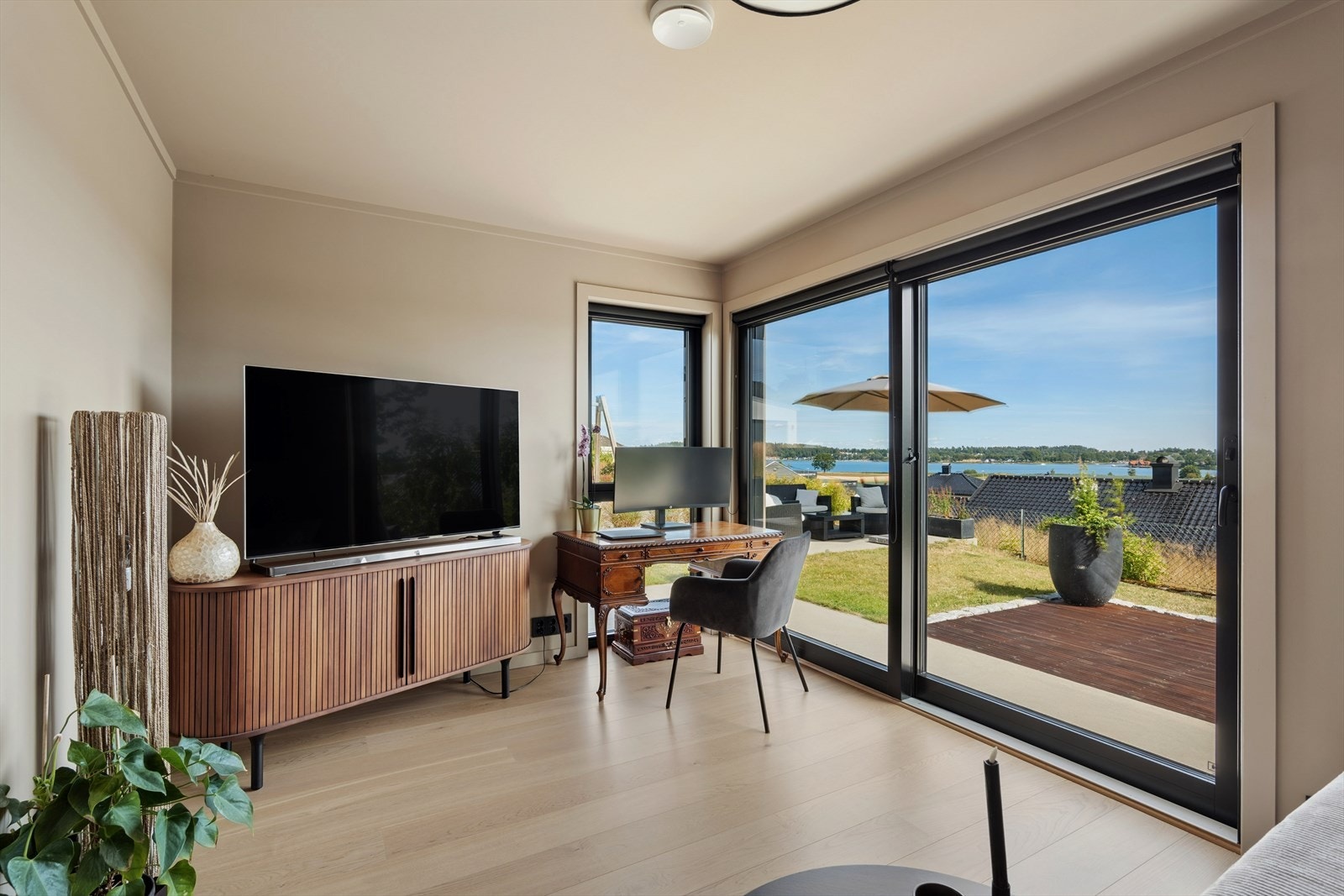 Lys og innbydende stue med store glassflater, vakker sjøutsikt og direkte adkomst til hage og terrasse. Galleribilde