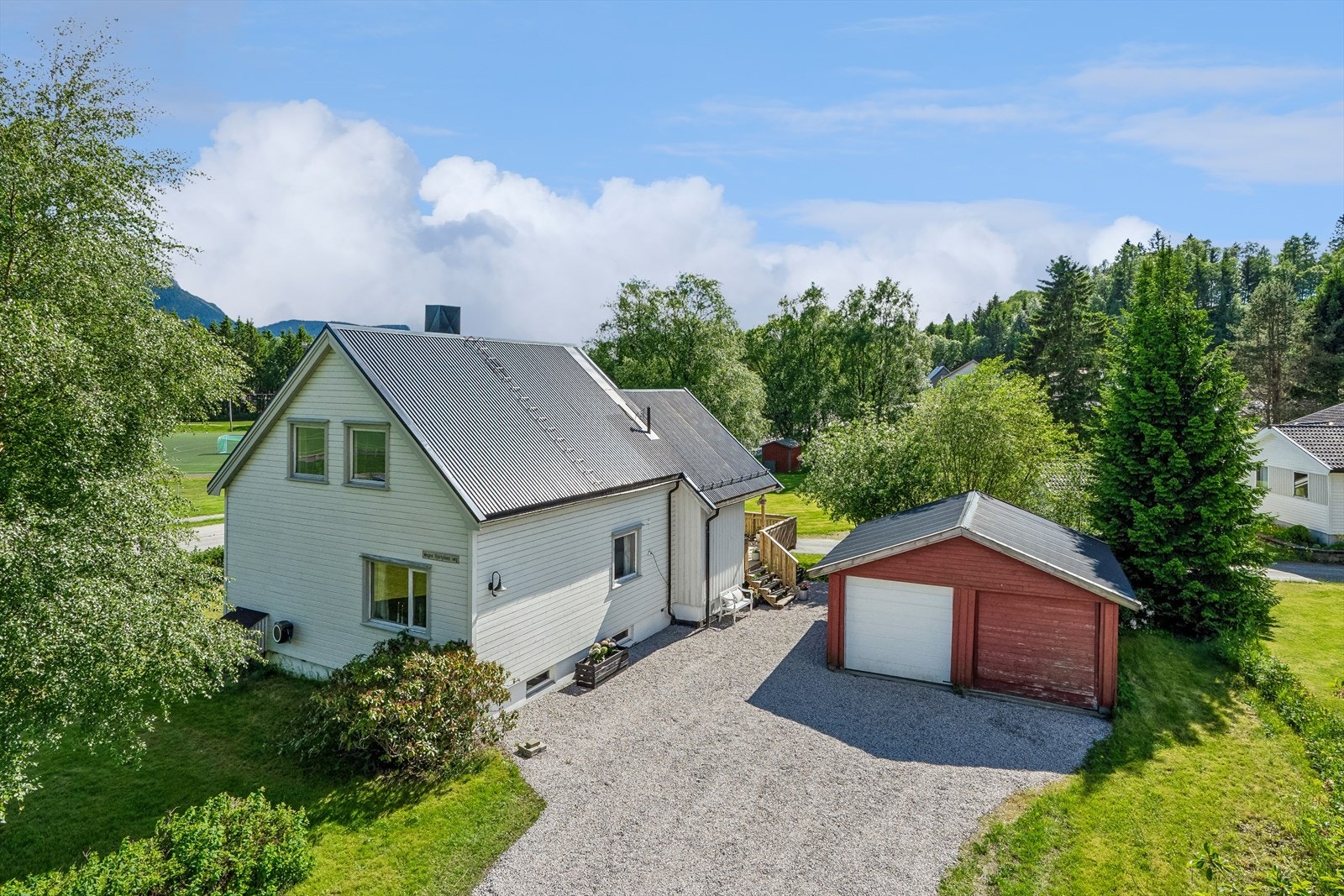 Romslig gårdsplass. Dobbeltgarasje. Hvit port med portåpner. Galleribilde