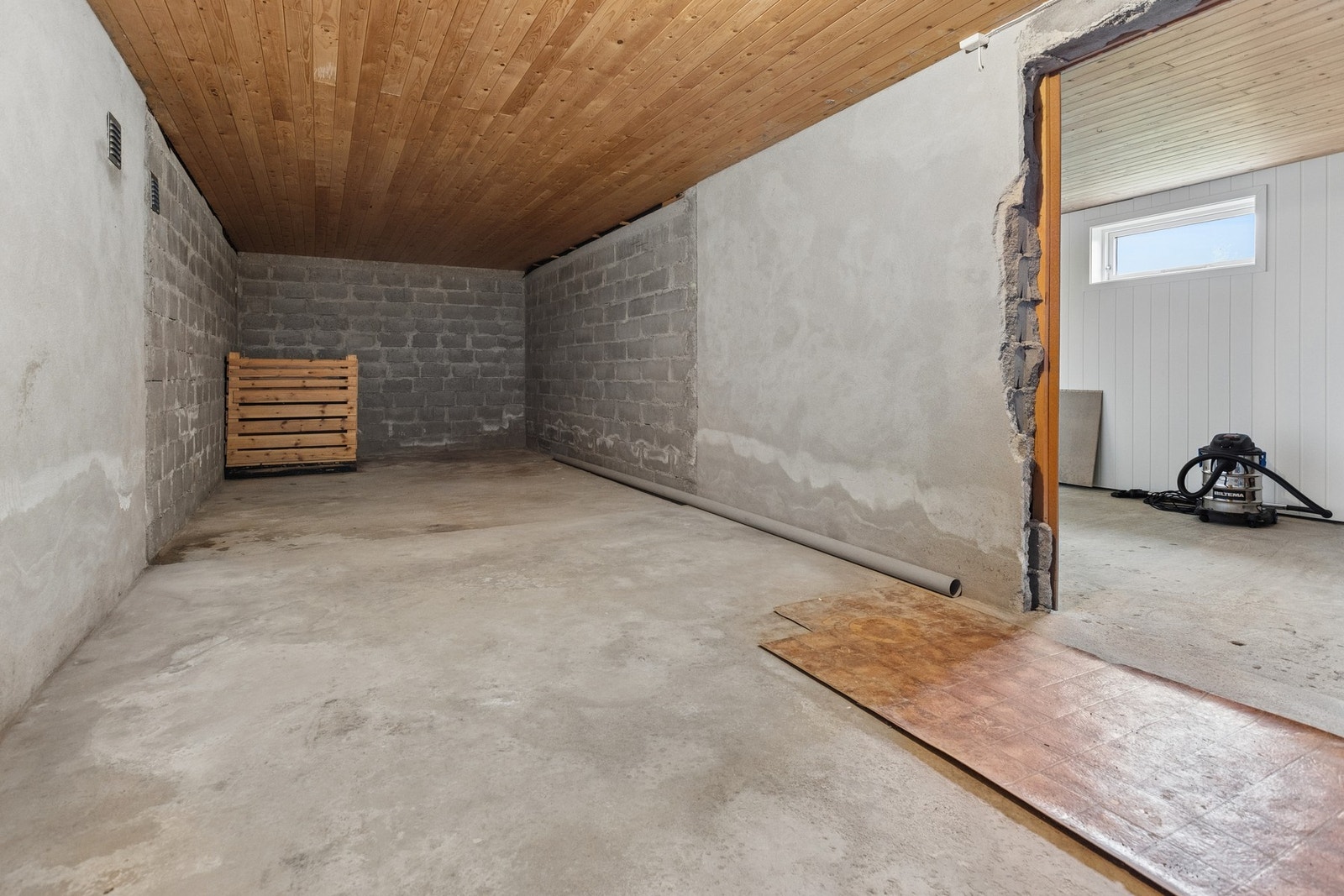 Kjellervegger av lettklinkerstein og himling av ubehandlet trepanel. Galleribilde