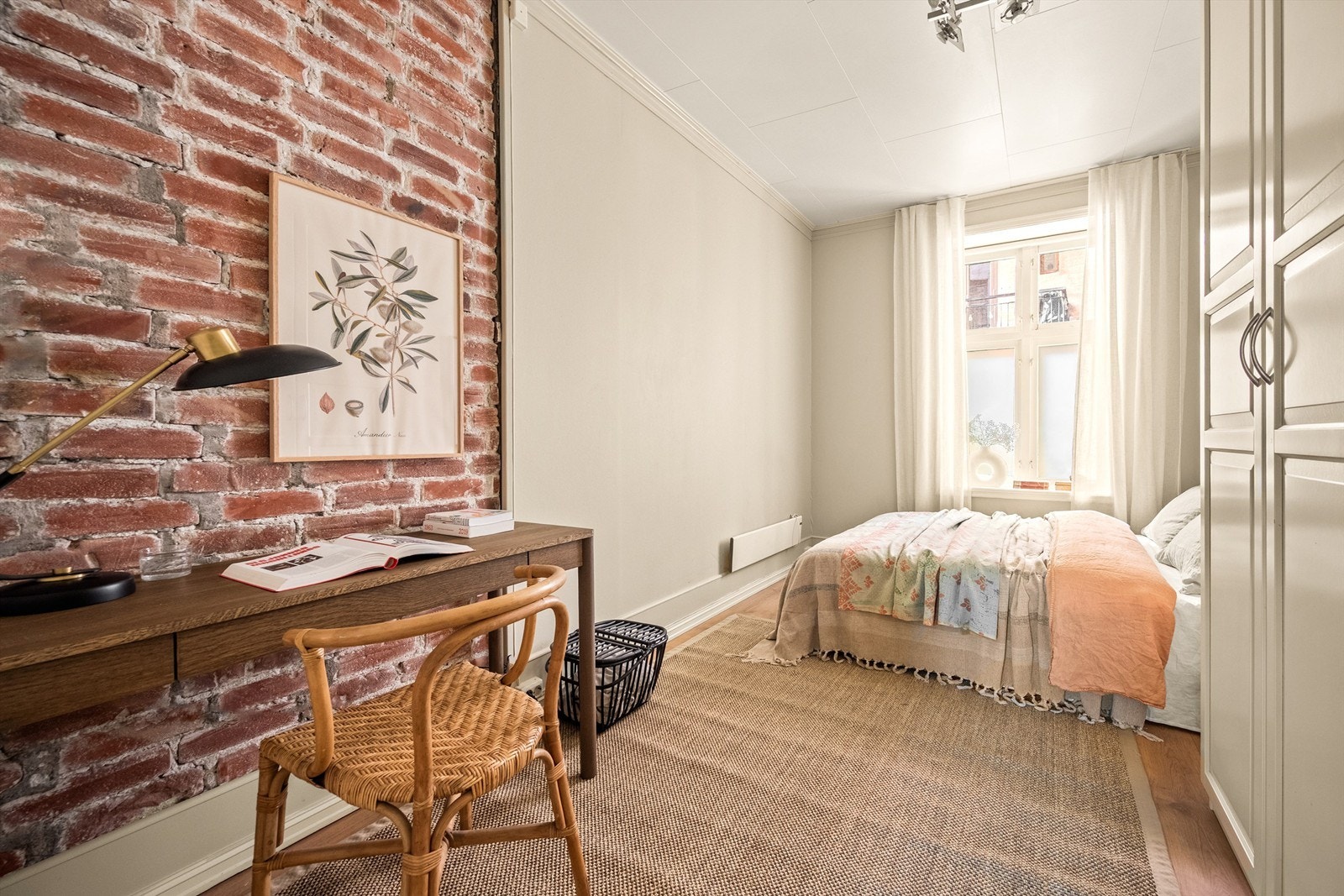 Et personlig soverom med en vakker original teglsteinsvegg og egen plass til hjemmekontor. Galleribilde