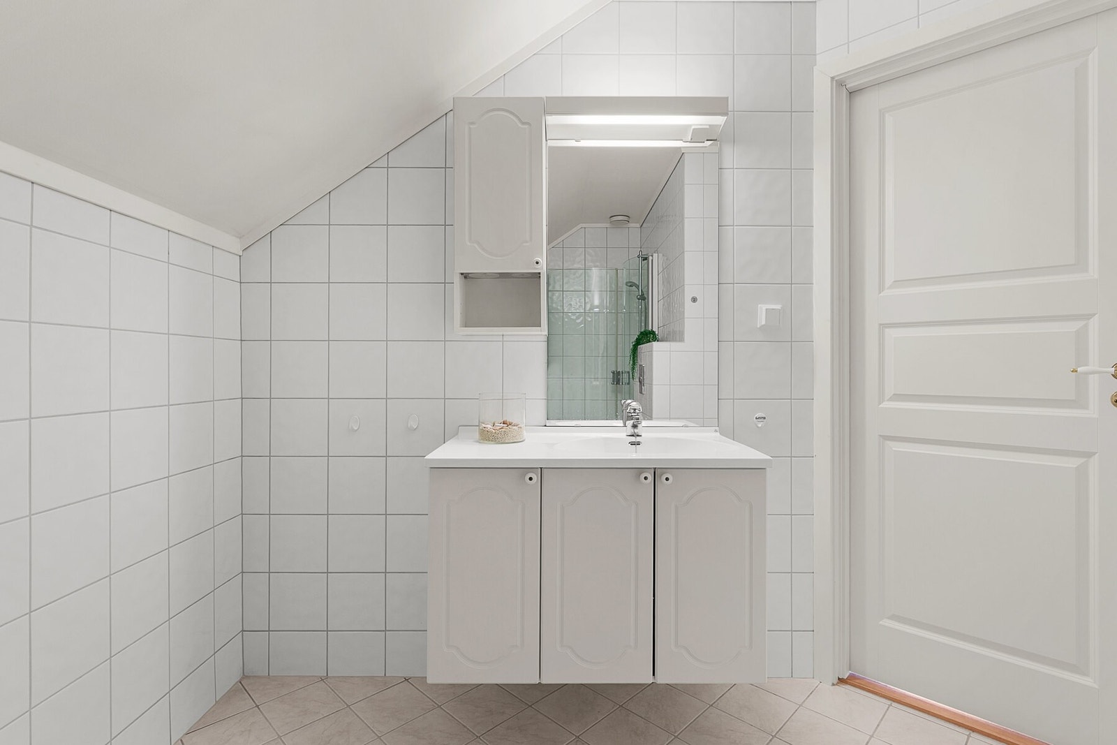 Badet er utstyrt med vegghengt klosett og servant med underskuffer og speil med belysning. Galleribilde