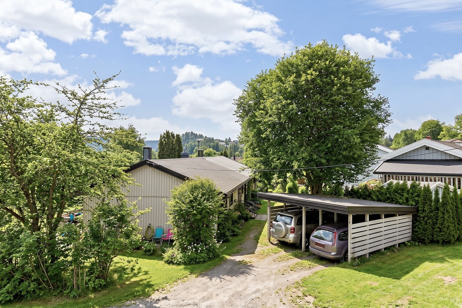 Parkering i carport samt biloppstillingsplass på gårdsplassen (Bilde er KI-generert fra vinter til sommer og avvik kan forekomme) Galleribilde