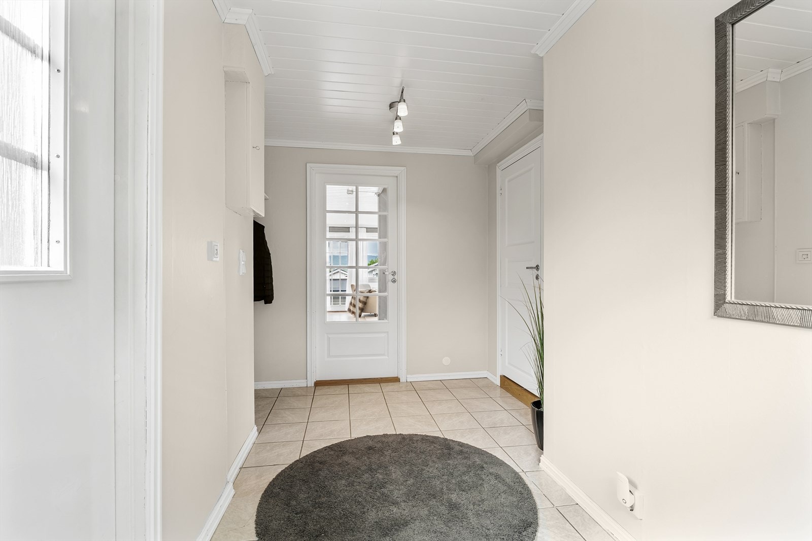 Entreen har flislagt gulv, lyse malte overflater og hvitmalt panel i taket. Galleribilde