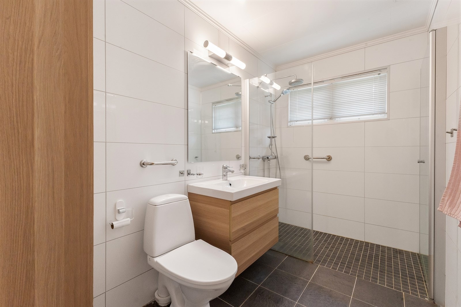 Moderne, pent bad med flislagte gulv og vegger gir badet et praktisk og lettstelt preg. Galleribilde