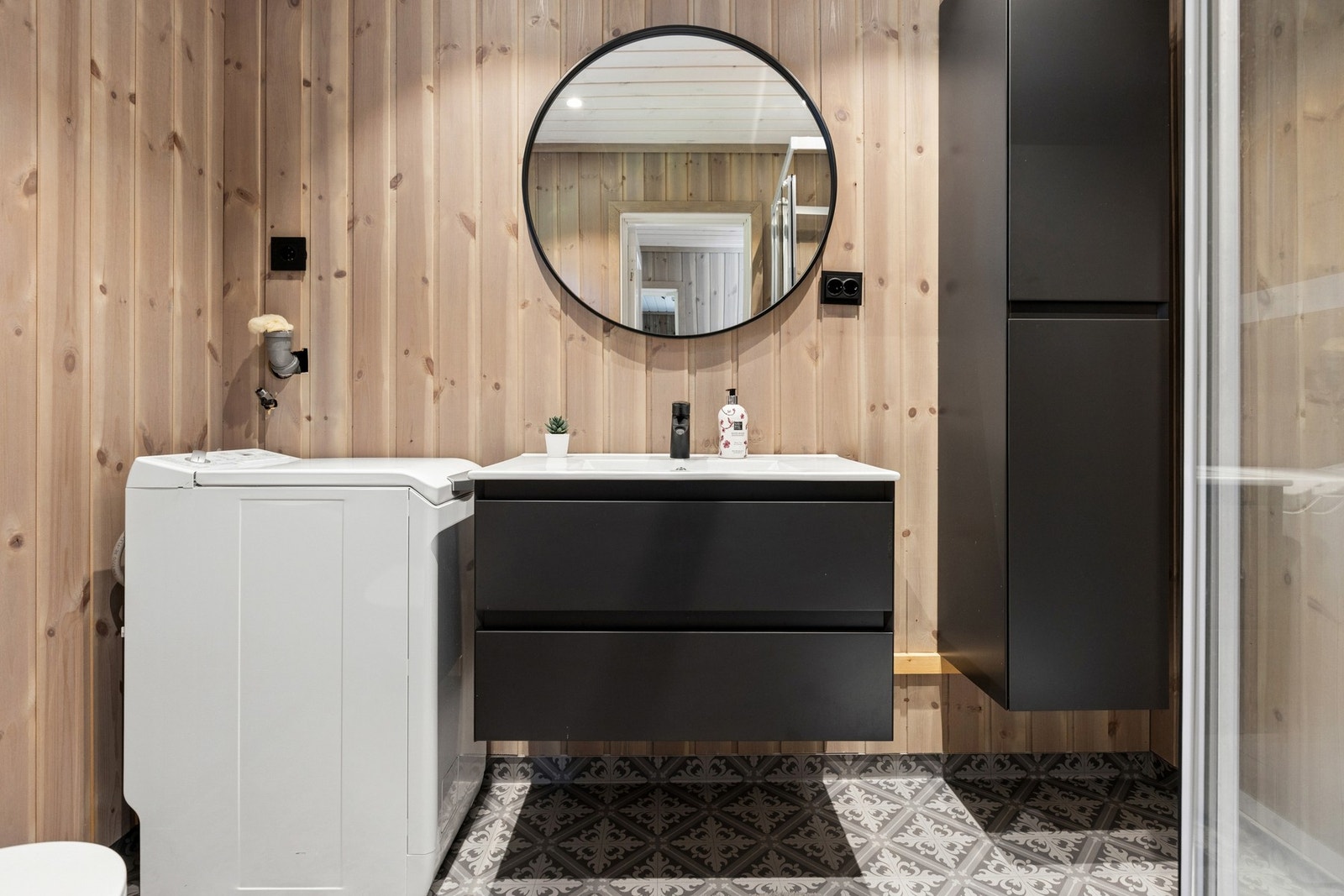 Badet har mønstrede gulvfliser og opplegg for vaskemaskin. Galleribilde