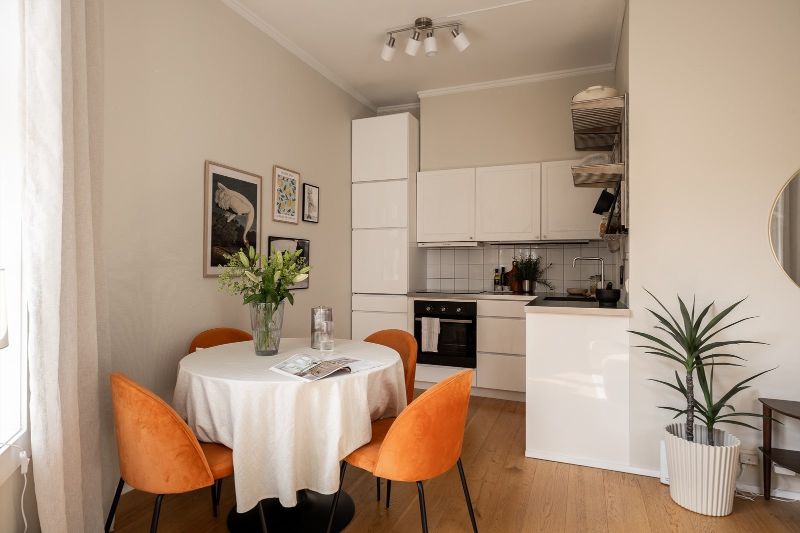 Pent kjøkken med innredning fra Kvik, med en lys og tidløs utførelse med profilerte/glatte fronter, fliser over benkeplaten og benkeplater i laminat. Galleribilde