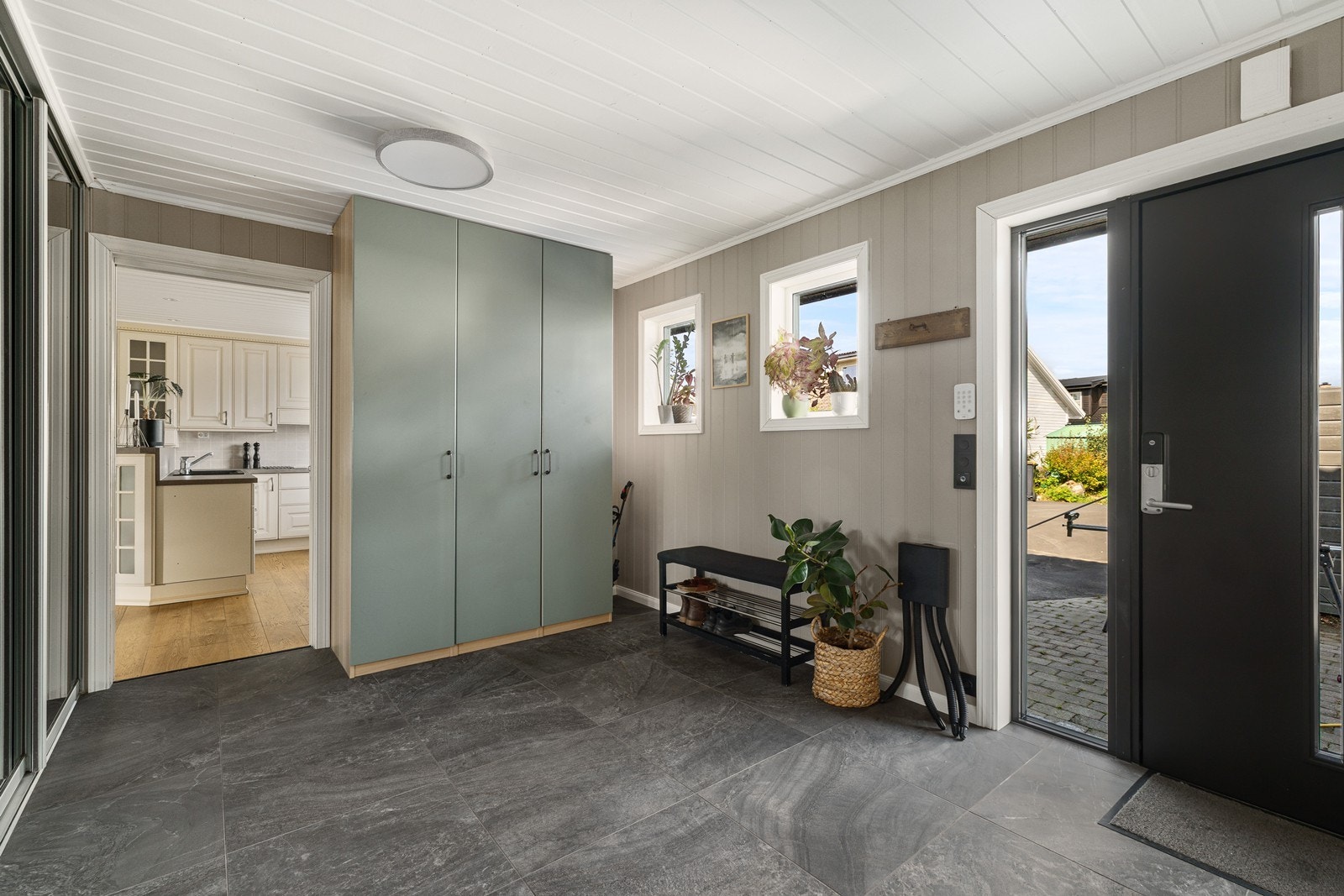 Hall med skyvedørsgarderobe samt flis på gulv og varmekabler Galleribilde