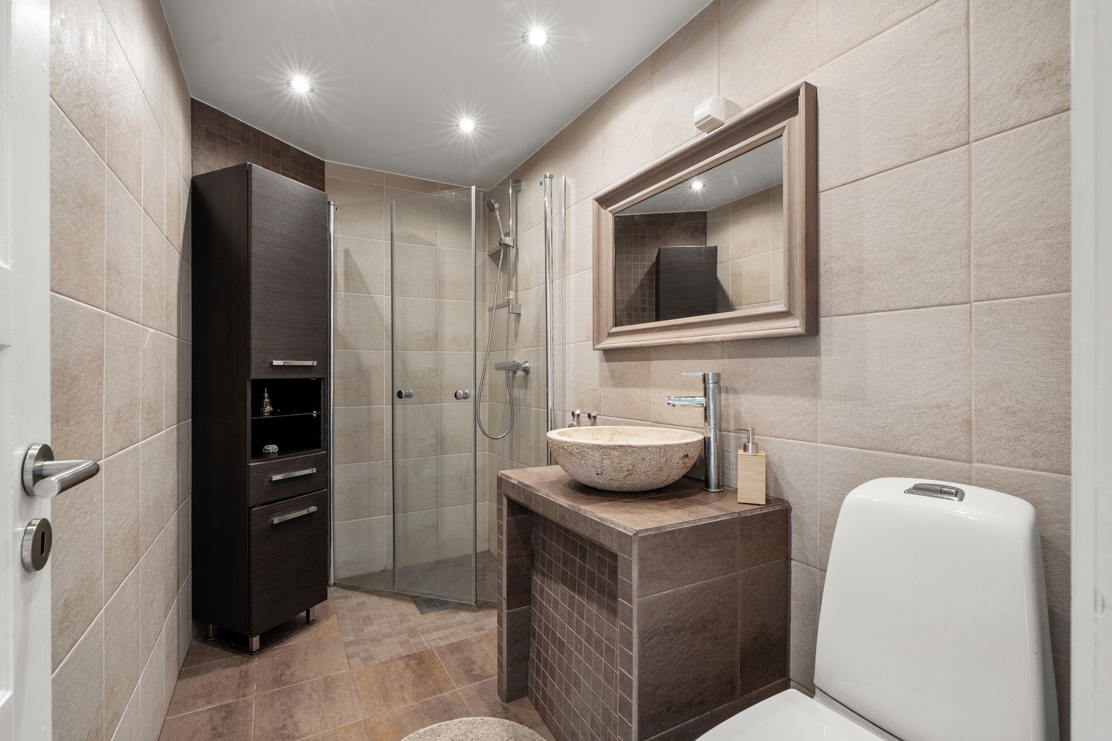 Badet i 1. etasje har et pent uttrykk med et stilrent flisvalg på gulv og vegg. Galleribilde