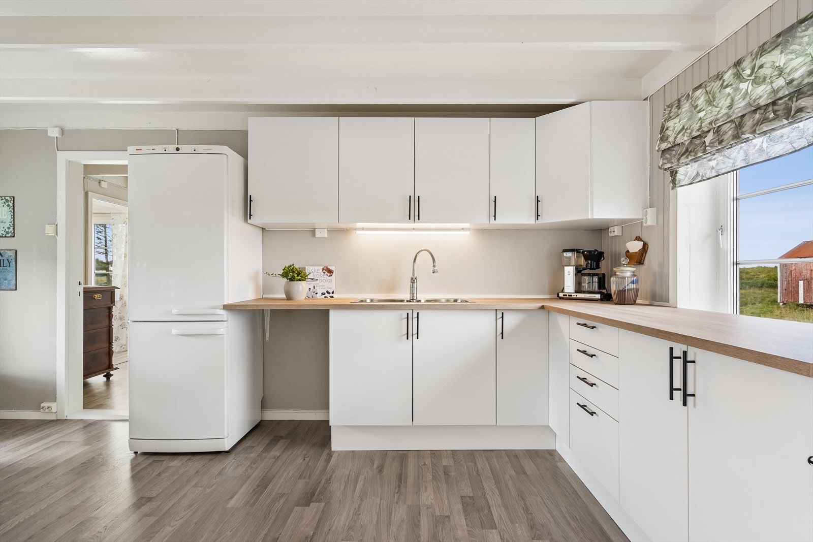 Kjøkkenet har fått et løft med en meget pent brukt innredning og ny benkeplate. Det er vinduer på begge sidene av kjøkkenet - dette gir rommet gjennomlys og rommet får et mer åpent og luftig preg. Galleribilde