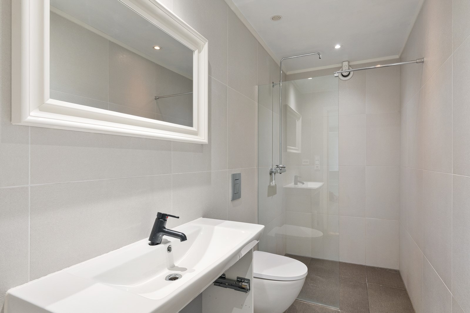 Badet er lekkert og helfliset, med vegghengt toalett, servant og dusj med glassvegg. Galleribilde