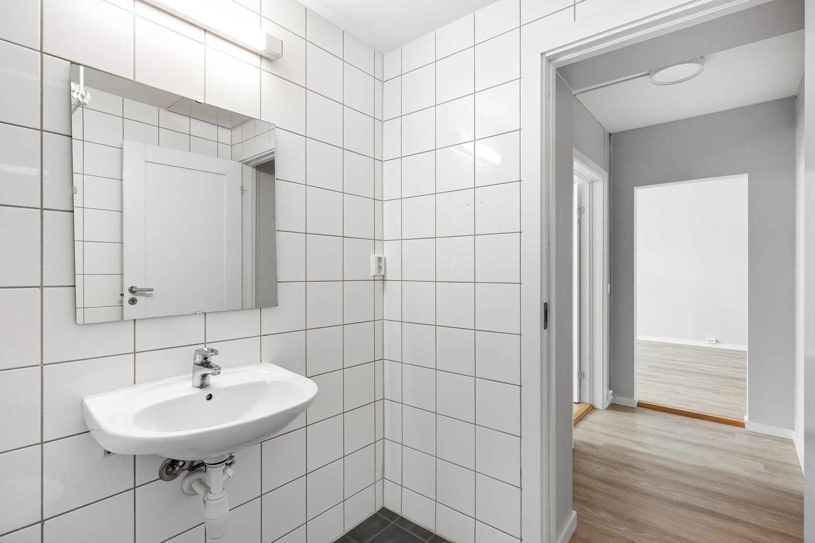 Badet er innredet med gulvmontert toalett, åpen dusjsone, servant og speil. Galleribilde