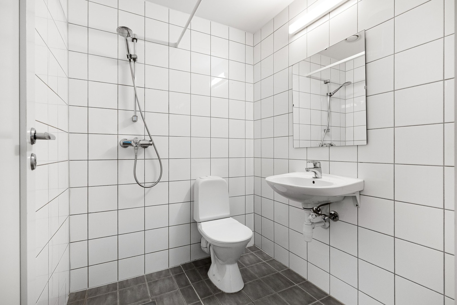 Flislagt bad med varmekabler i gulv og opplegg for vaskemaskin. Galleribilde