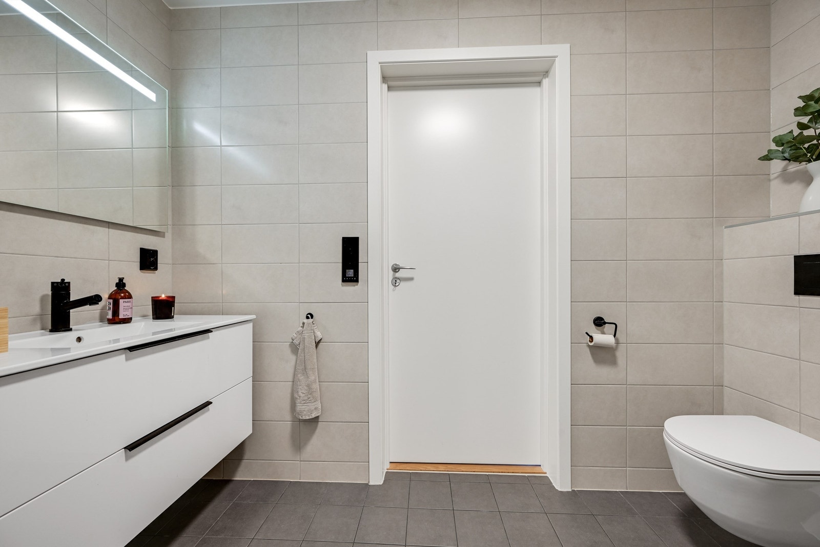 Badet fremstår moderne og innbydende med flislagte gulv og vegger, gulvvarme, vegghengt toalett og dusjnisje med glassdør. Galleribilde