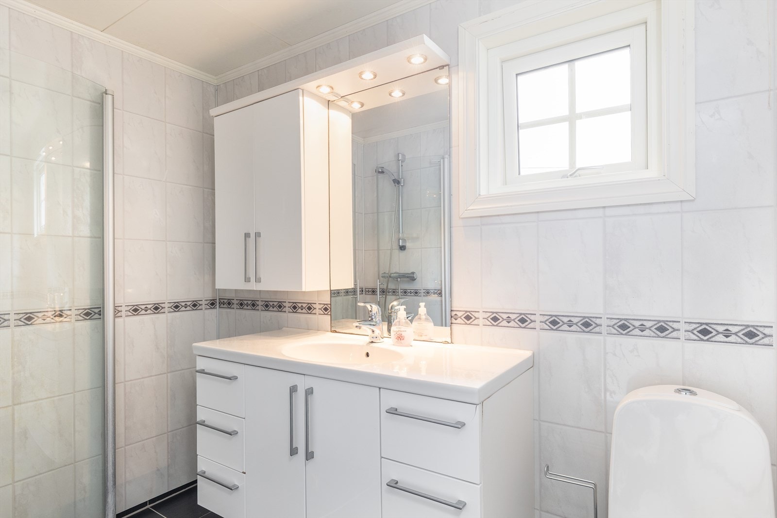 Badet i 1. etasje har baderomsplater på veggene og keramiske fliser på gulvet med varmekabler. Galleribilde