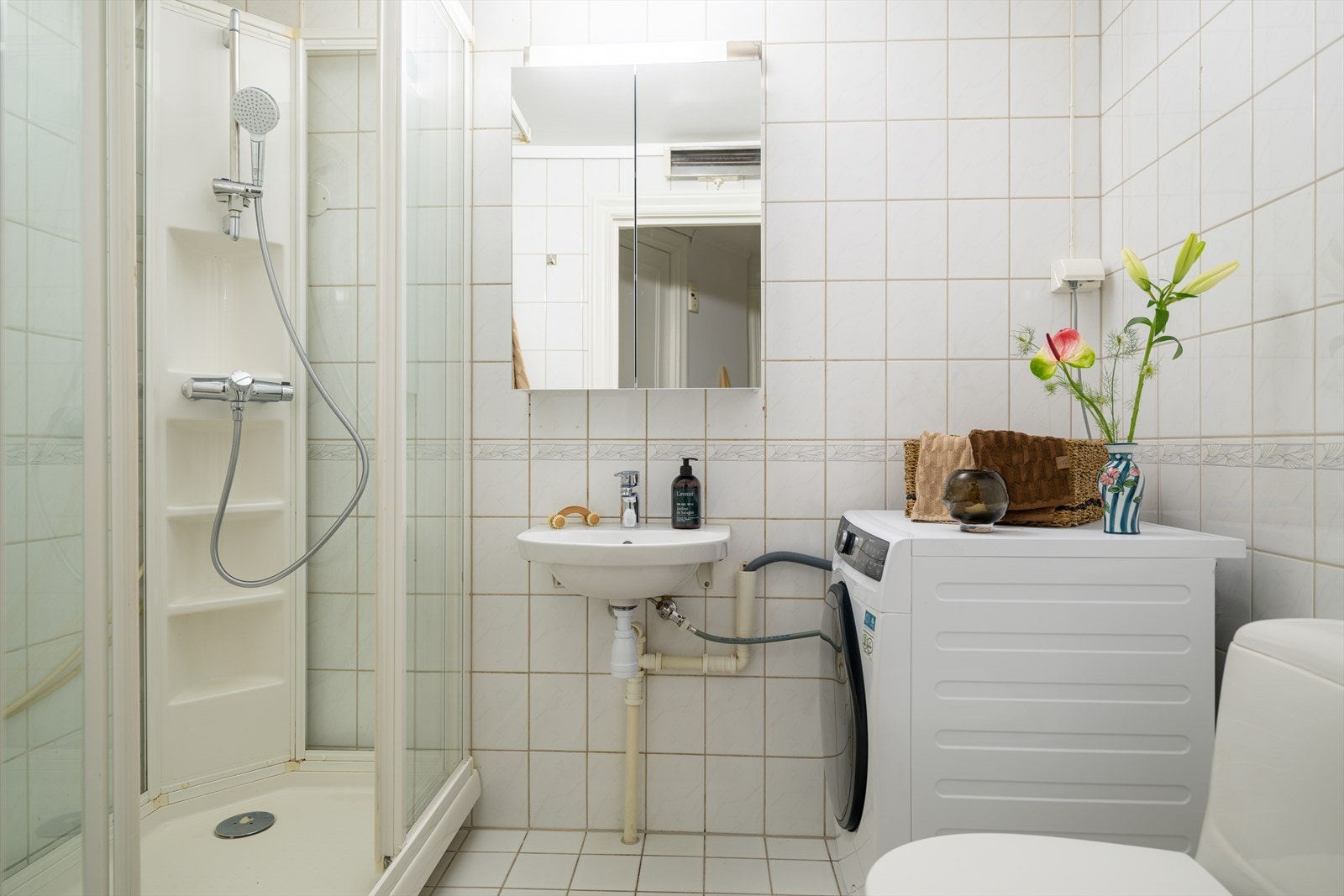 Det arealsmarte badet har tidløse lyse fliser på gulv og vegger. Galleribilde