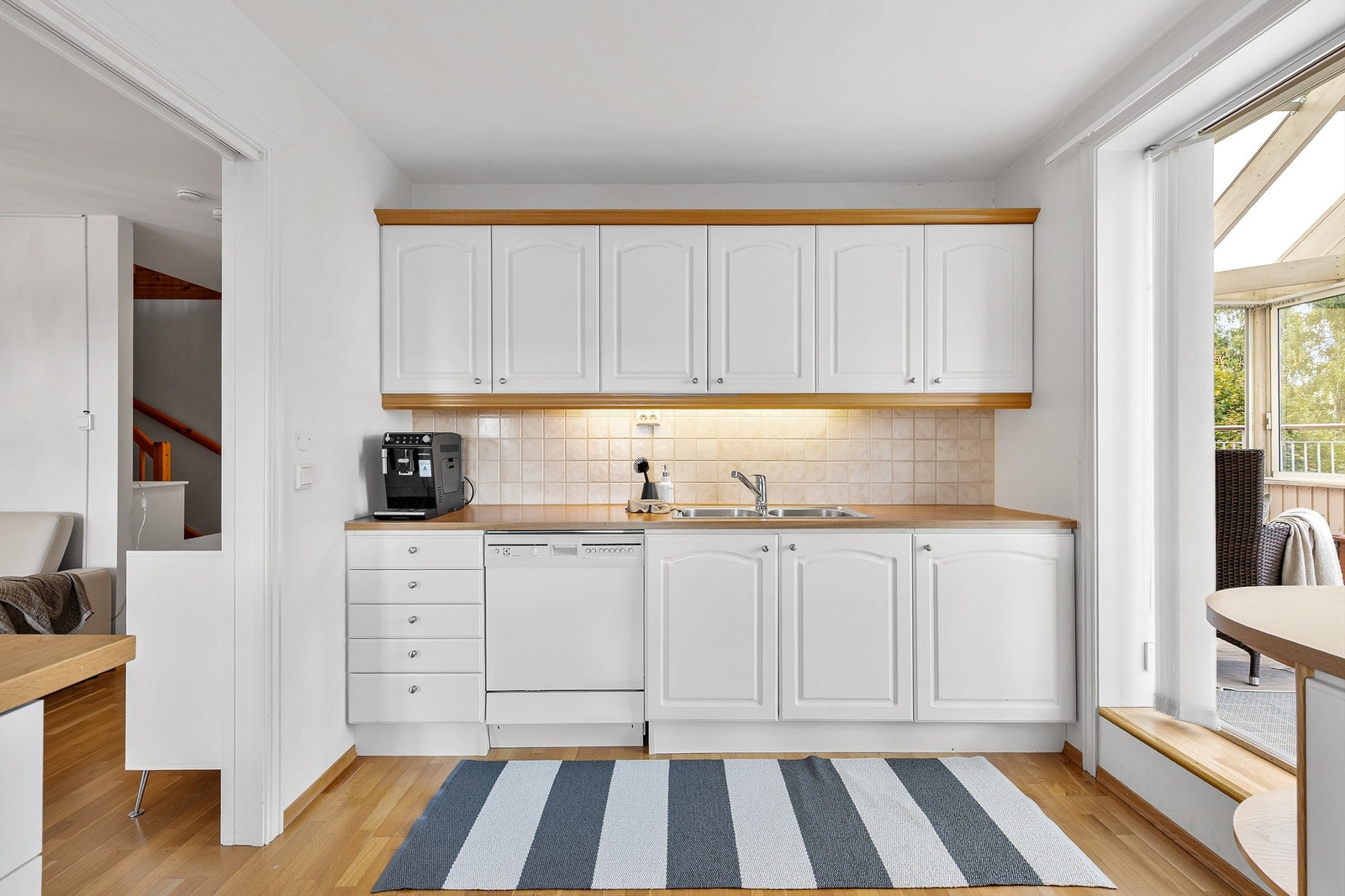Kjøkkeninnredning fra byggeår med profilerte fronter og benkeplate med laminert overflate. Kjøkkenvask med armatur. Galleribilde