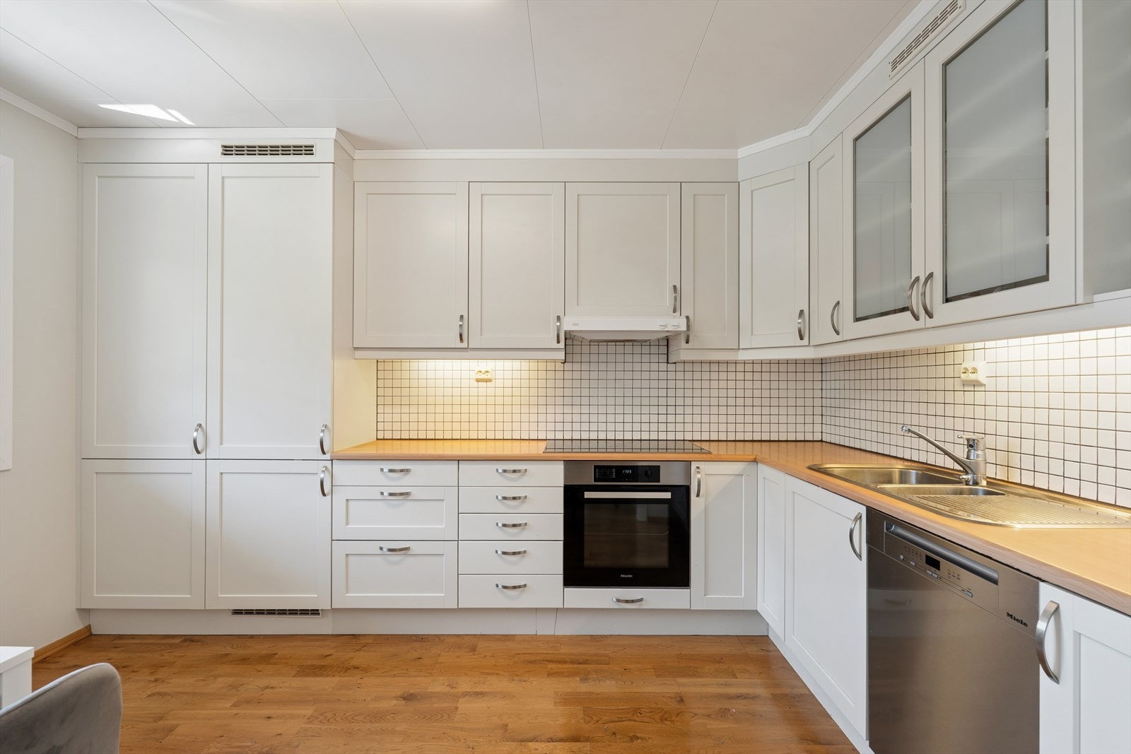 Kjøkkenet har en tidløs innredning med profilerte fronter, rikelig med skapplass og innebygd stekeovn fra Miele. Galleribilde
