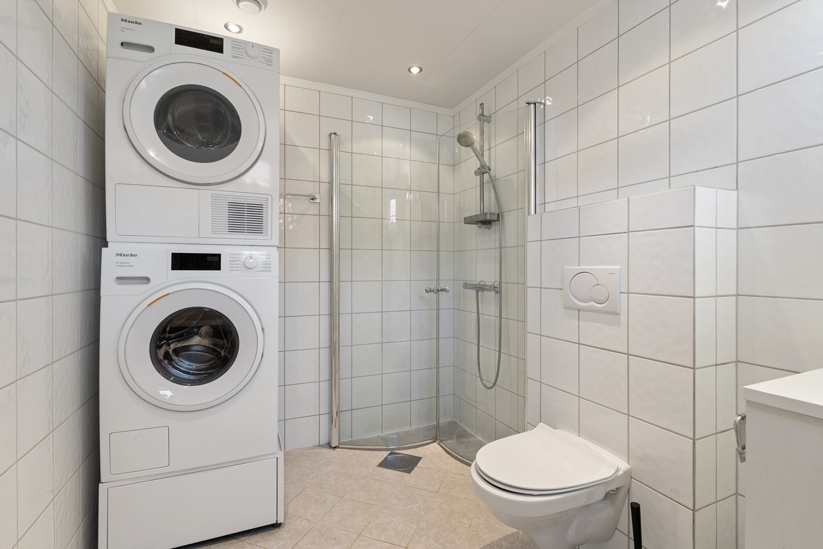 Badet er helfliset og har en praktisk vaskesøyle med maskiner fra Miele. Galleribilde
