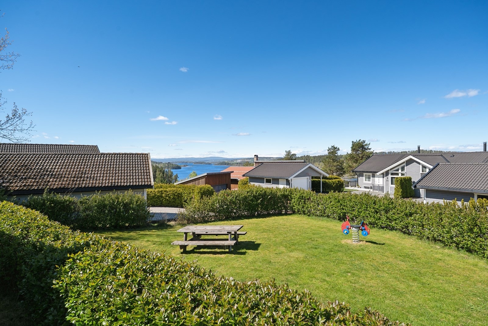 Fellesarealene er pent opparbeidet med plen og sittegrupper, med utsikt mot vannet i det fjerne. Galleribilde