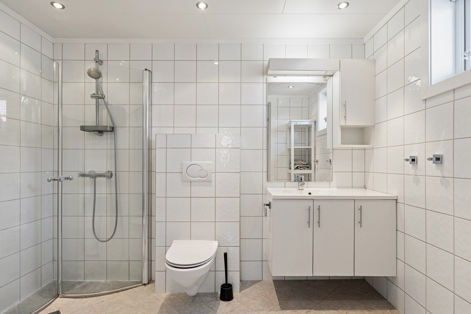 Lyst og pent bad utstyrt med dusjhjørne, vegghengt wc og en god baderomsinnredning. Downlights i tak. Galleribilde