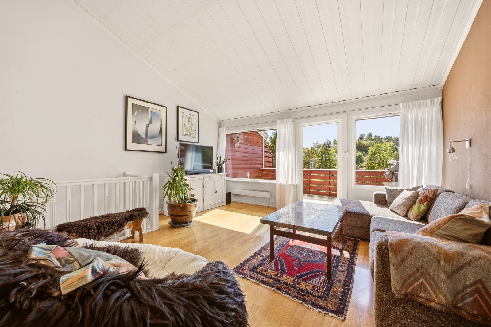 Store balkongdører åpner opp mot den solrike uteplassen og slipper rikelig med naturlig lys inn i stuen. Galleribilde