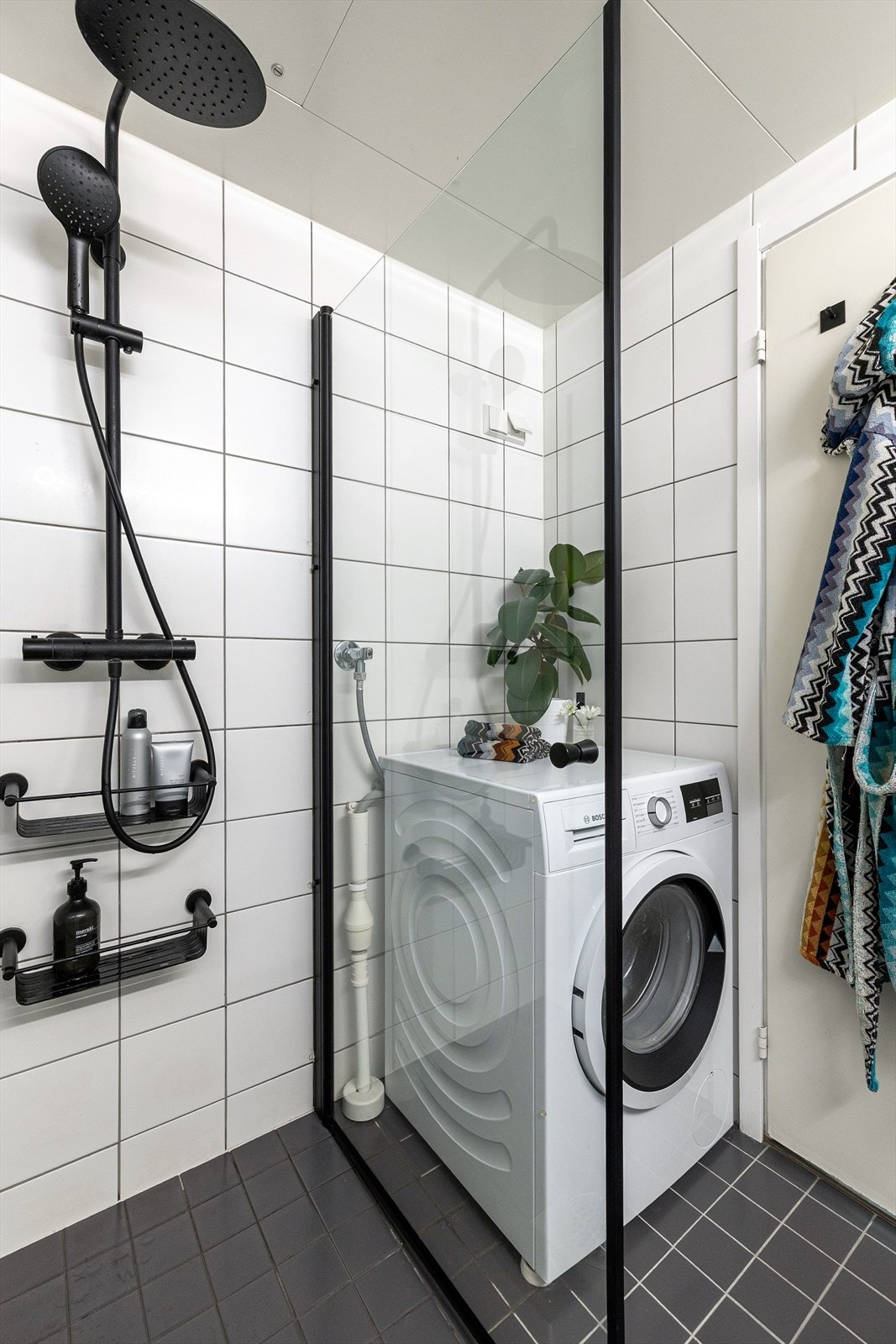 Badet er innredet med veggmontert toalett, dusjplass med inn- og utadslående dusjvegger og baderomsmøbel med skuffer og servant med ettgreps blandebatteri. Galleribilde
