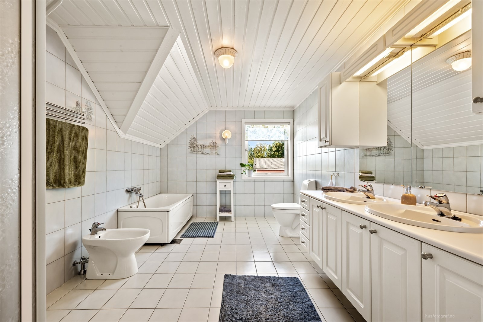 Badet er fra byggeår med flislagte vegger og malt trepanel i himlingen. Flislagt gulv med elektriske varmekabler styrt via termostat. Galleribilde