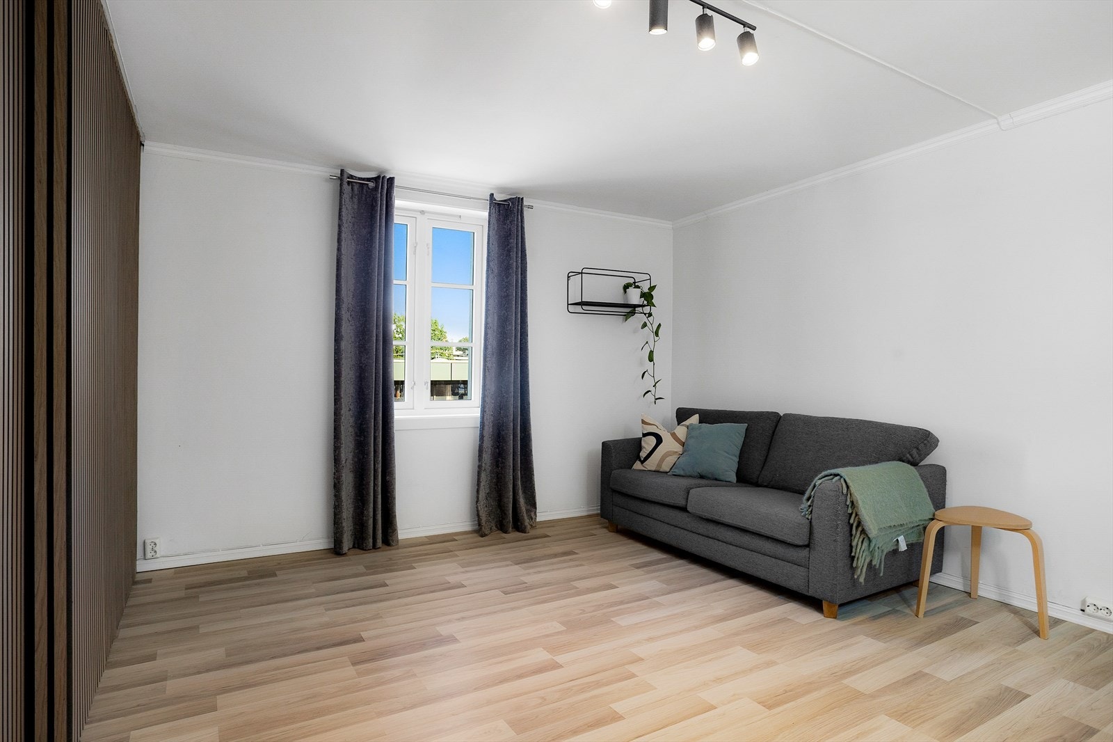 Stuen har en vegg med spilepanel og gjennomgående laminatgulv. Galleribilde