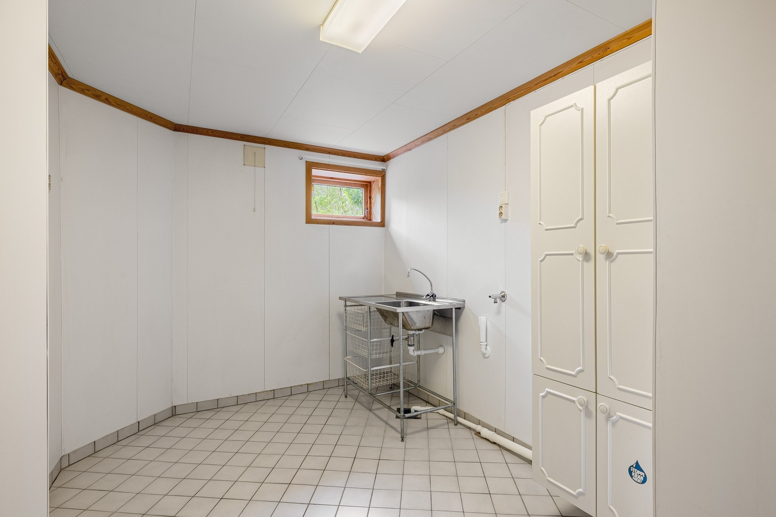 Vegg i vegg med badet ligger et vaskeorm. Standarden er eldre, og renovering må påregnes. Galleribilde