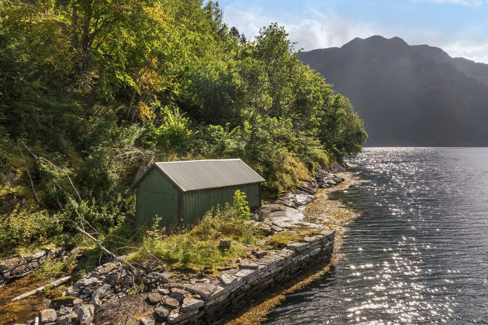 Nede ved sjøen ligg naustet som er oppført på i bindingsverk på grunnmur i naturstein Både tak og veggar er kledd med A-takplater. Galleribilde