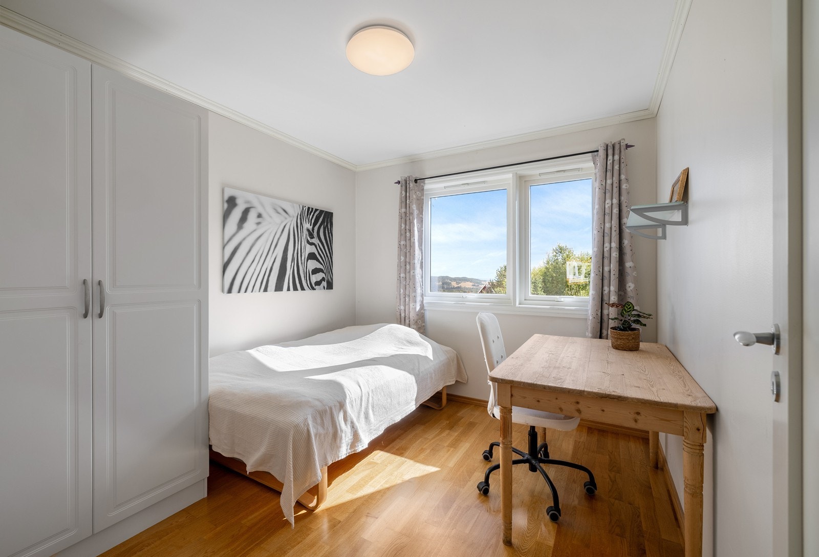 Lyst og romslig soverom med god plass til seng, garderobeløsning og skrivebord. Galleribilde