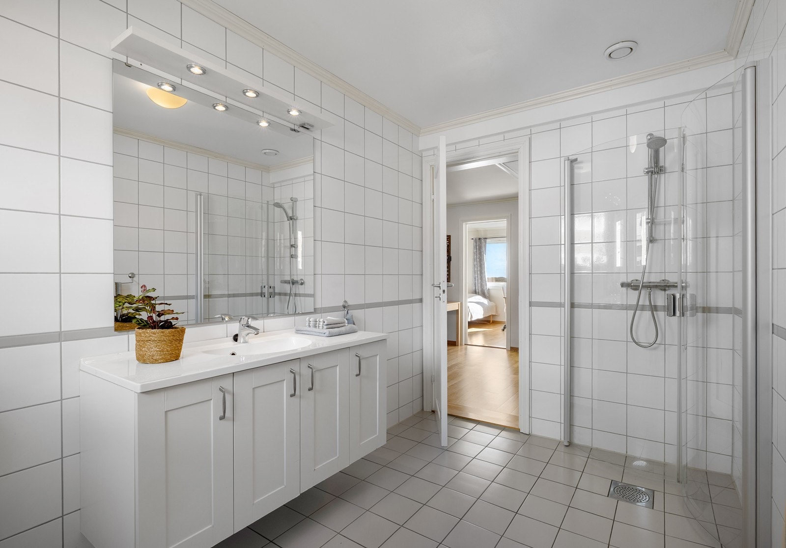 Badet har en praktisk innredning med romslig dusjsone og godt med oppbevaringsplass. Galleribilde