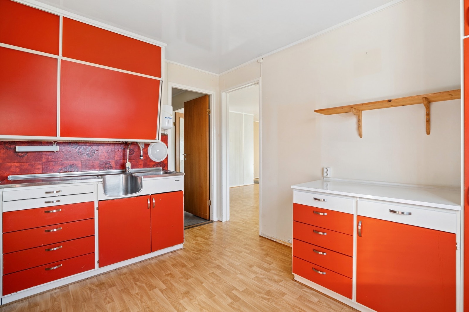 Kjøkkeninnredning med glatte fronter og benkeplate i laminat og rustfritt stål. Galleribilde