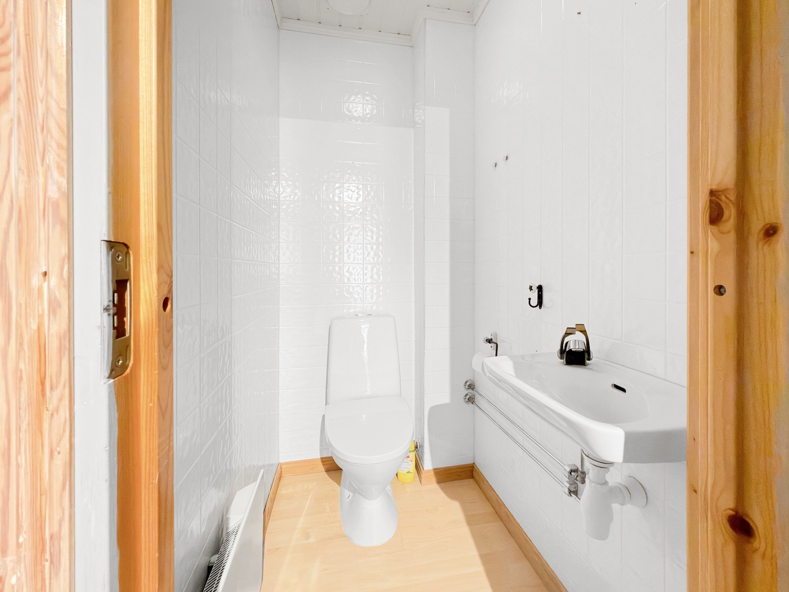 Toalettrom med laminat på gulv, våtromsplater på vegger og himling med MDF-panel. Sanitærutstyr med klosett og vegghengt servant med 2-greps blandebatteri. Galleribilde