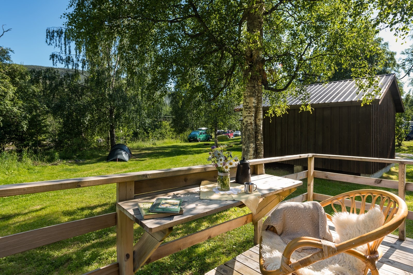 Fra terrassen ser man utover campingplassens åpne og grønne arealer. Galleribilde
