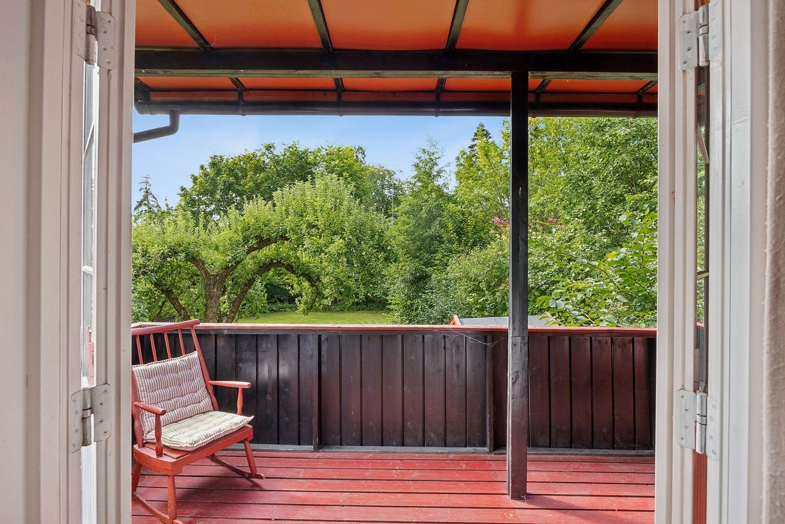 Sørvestvendt veranda på ca. 12 m² med direkte trappeadkomst til hagen. Verandaen er opprinnelig godkjent som to separate balkonger uten trapp. Balkongdør til spisestuen er fjernet. Endringene er søknadspliktige fasadeendringer. Galleribilde