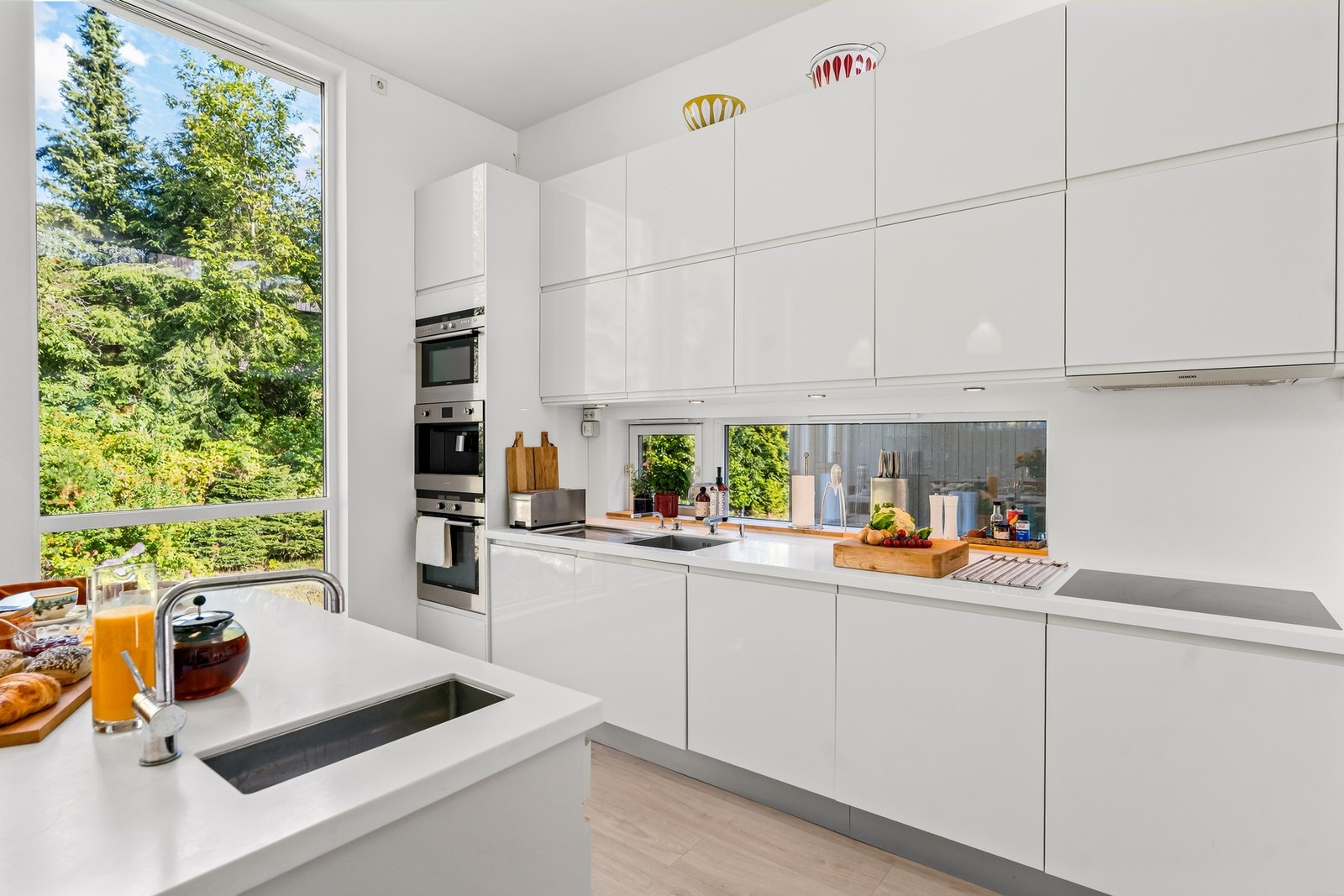 Kjøkkenet er fra byggeåret og har stilren kjøkkeninnredning fra HTH med god skap- og benkplass. Benkeplatene er utført i kompositt / Corian med underlimt metallvask fra Blanco og ettgreps kjøkkenarmatur fra Vola både på kjøkkenøya og i benkeplanten langs Galleribilde