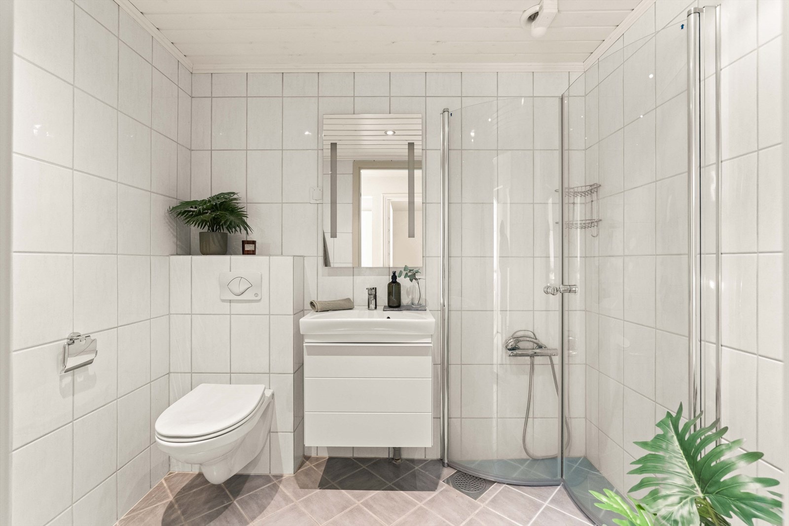 Badet i 2. etasje er flislagt og innredet med servantmøbel, vegghengt toalett og dusjløsning. Galleribilde