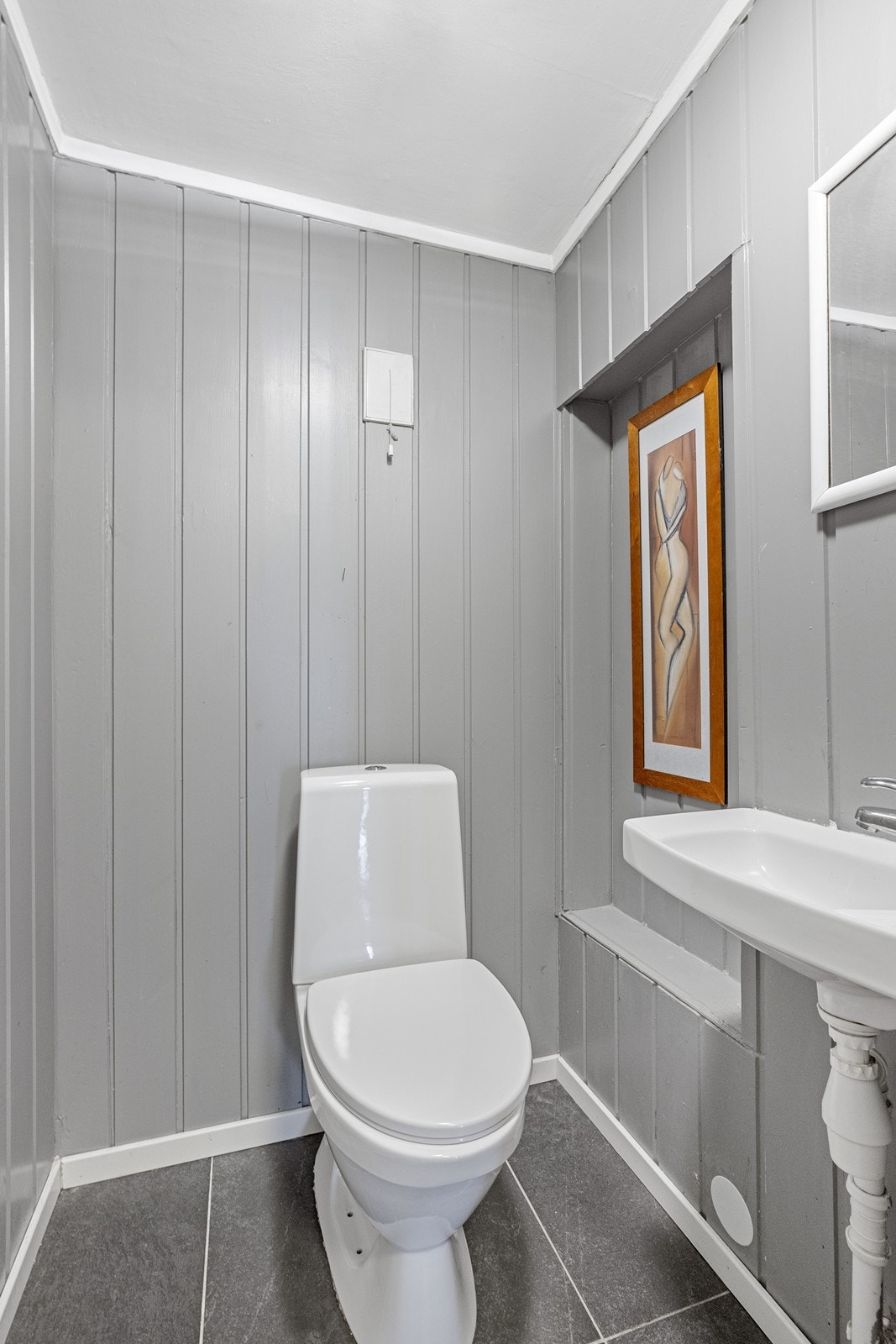 Wc-rommet er utstyrt med gulvstående toalett og enkel servant, med ventilasjon via veggventil. Galleribilde