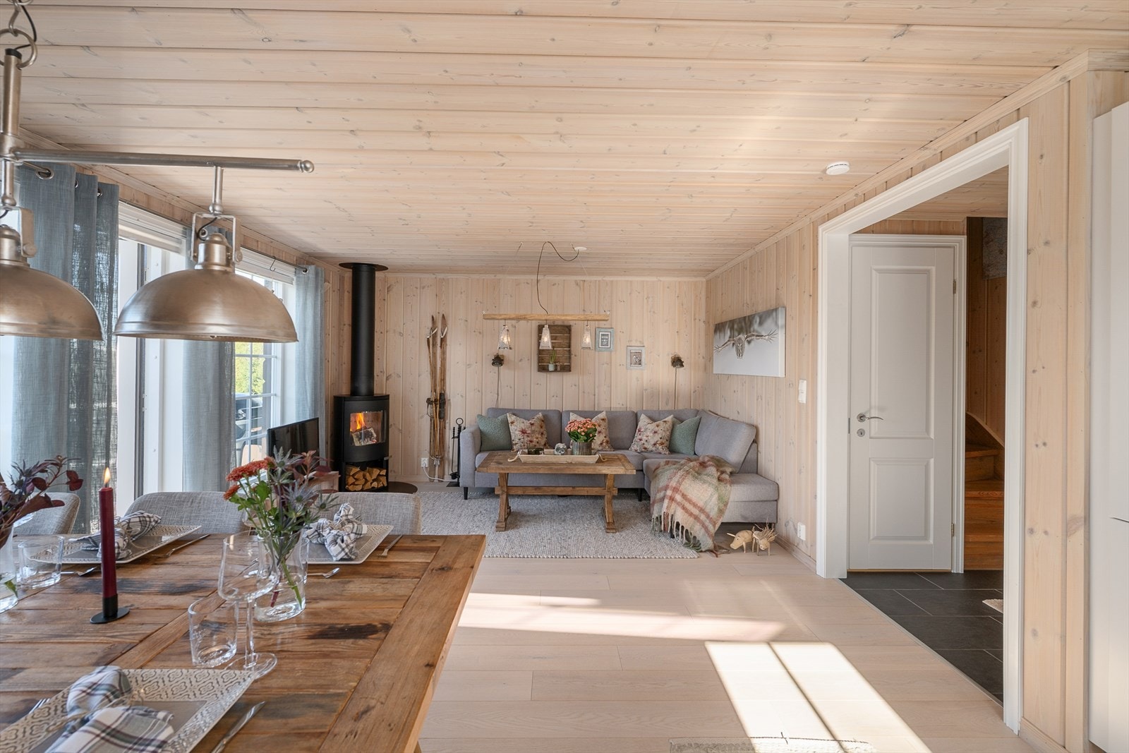 Åpen stue- og kjøkkenløsning med parkett på gulv og panel på vegger og i tak. Galleribilde