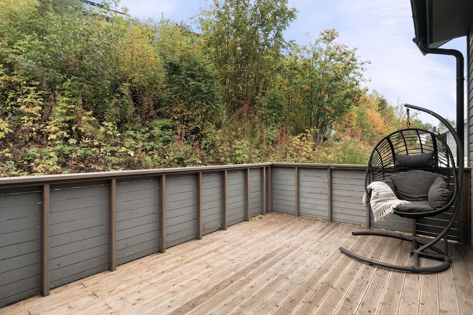 Stor, lun og skjermet terrasse omgitt av grøntarealer som skaper en hyggelig og privat oase.