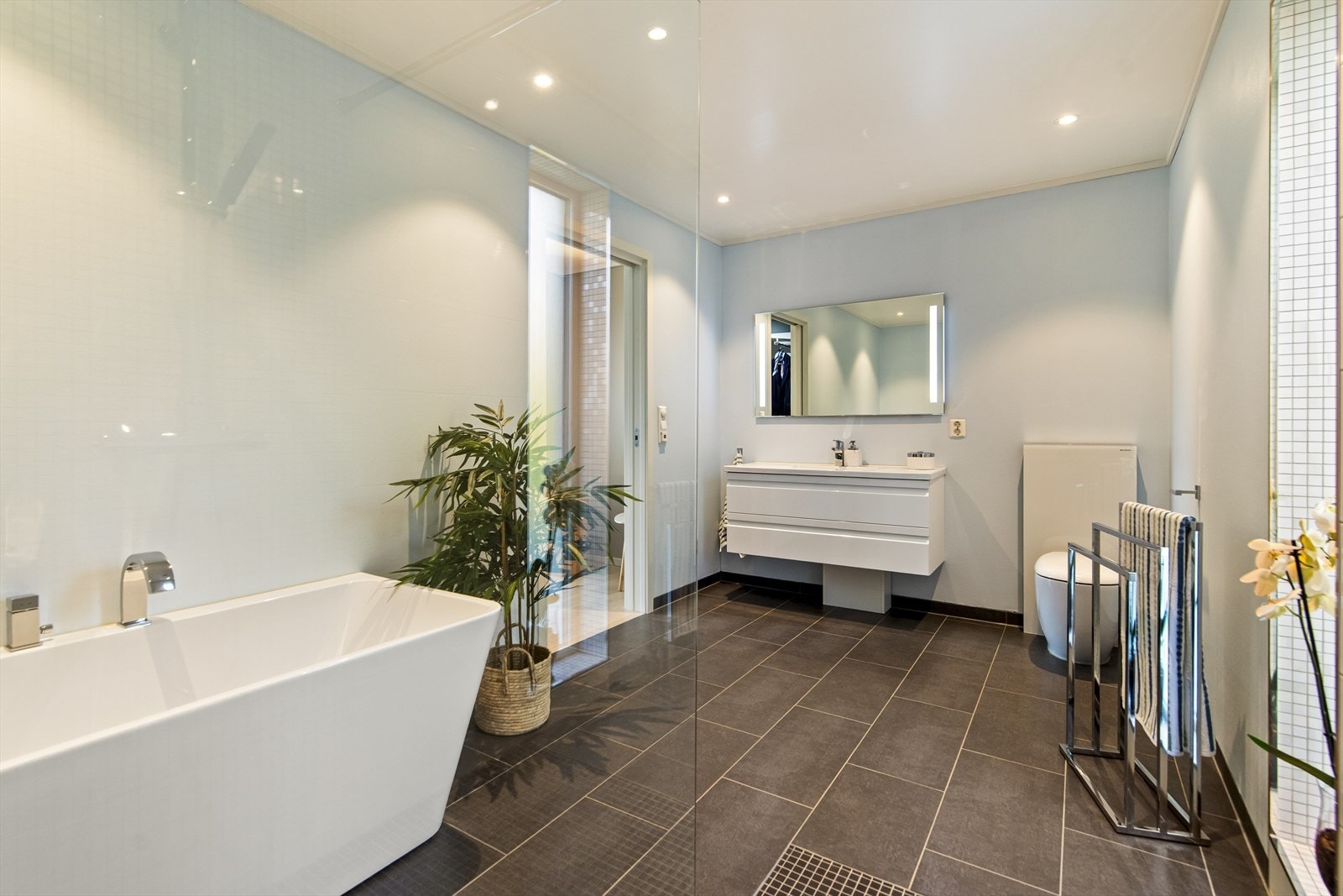 Badet er romslig og funksjonelt innredet med servant nedfelt i skuffeinnredning og overhengende speil, dusjnisje med glassvegg, badekar, samt toalett. Galleribilde