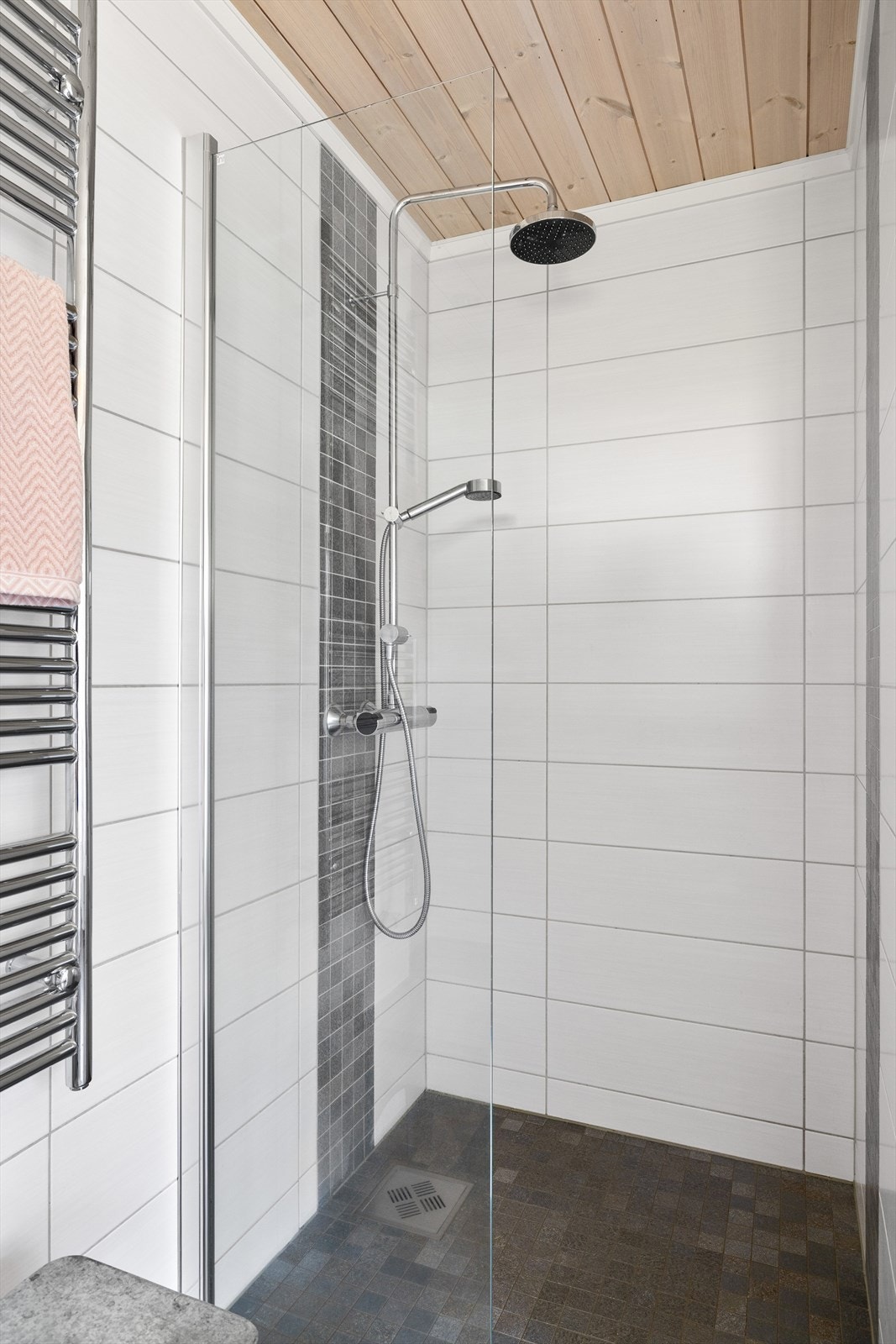 Baderommet er også utstyrt med dusjnisje med glassvegg og både hånd- og regnfallsdusj, vegghengt håndkleholder og vegghengt toalett. Galleribilde