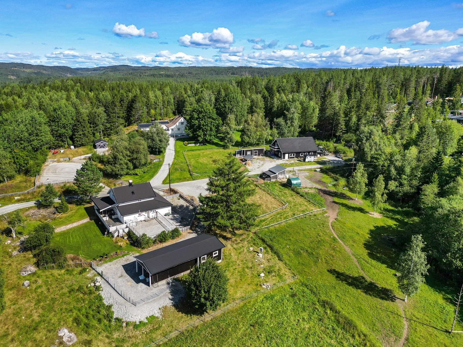 Dronebilde som viser gårdstunet og eiendommens gode plassering i terrenget. Galleribilde