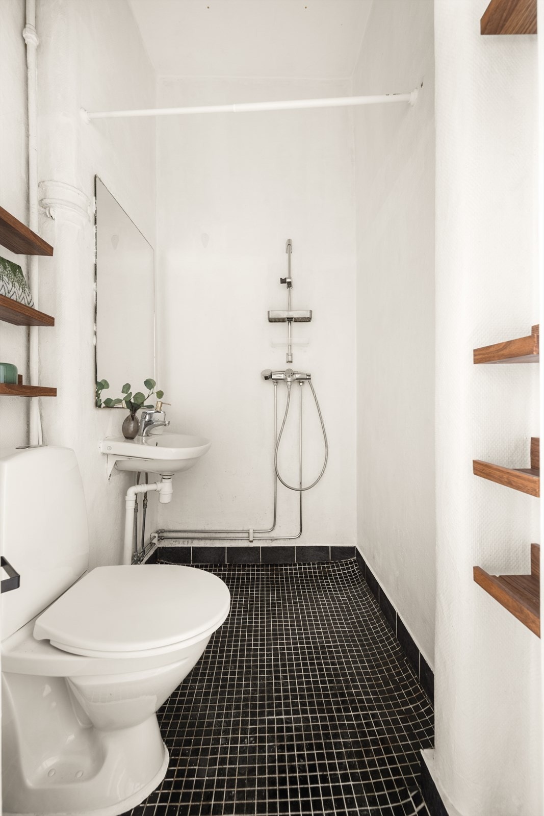 Badet har overflater med fliser på gulvet, strié på veggene med varmelampe og malt himling. Badet er utstyrt med toalett, vegghengt servant og dusjhjørne. Galleribilde