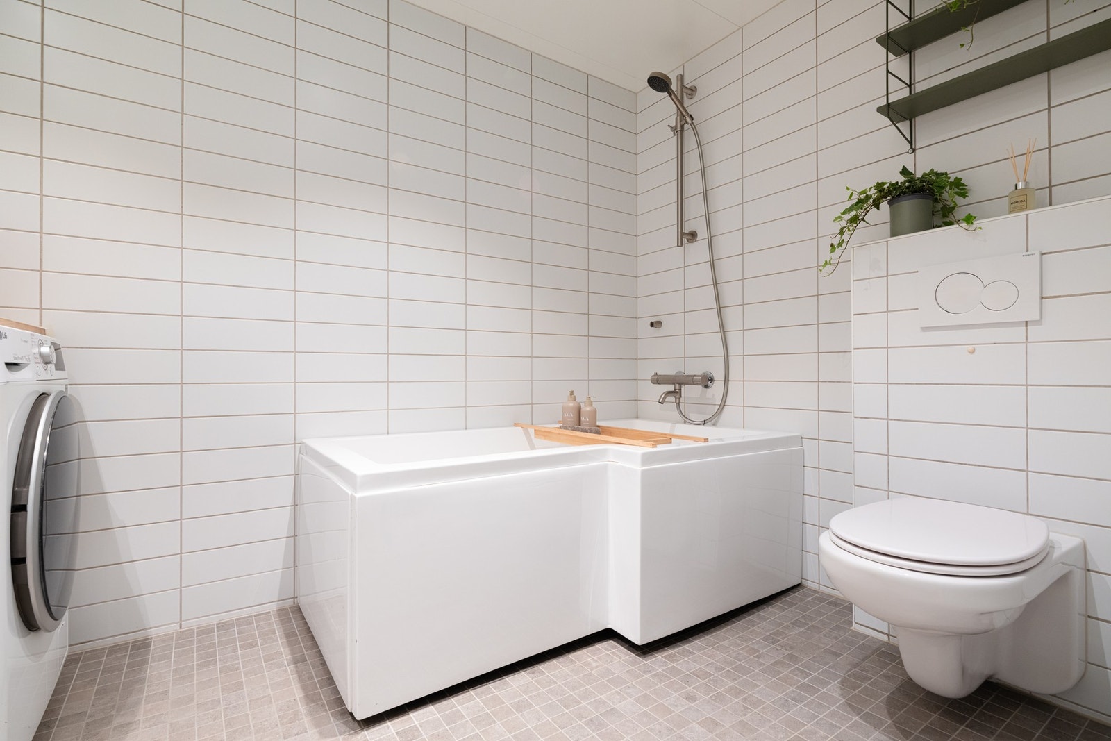 Videre er det vegghengt toalett og badekar med dusj. Badet benyttes som boligens vaskerom med opplegg for vaskemaskin og plass til tørketrommel. Galleribilde